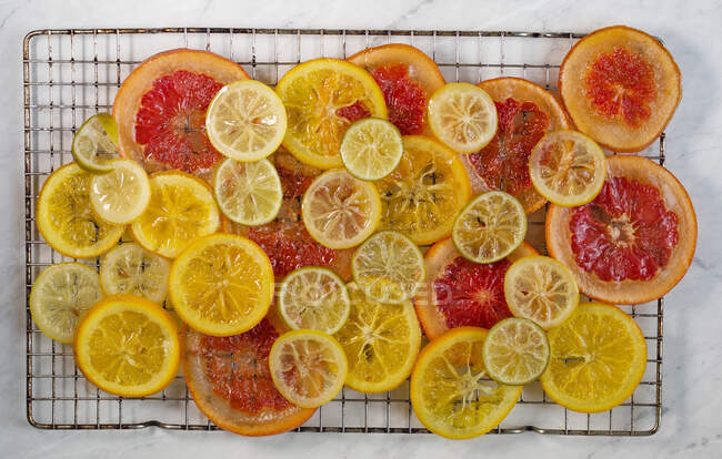 Цитрусовые фруктовые ломтики, приготовленные в сиропе, на подносе с капельницей (вид сверху)) — стоковое фото