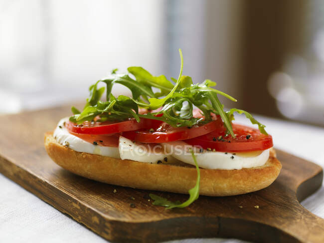Baguette slice topped with mozzarella, tomatoes and rocket — Stock Photo