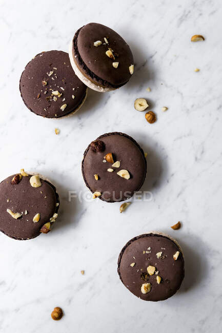 Nougat macarons with grated hazelnuts on white marble surface — Stock Photo