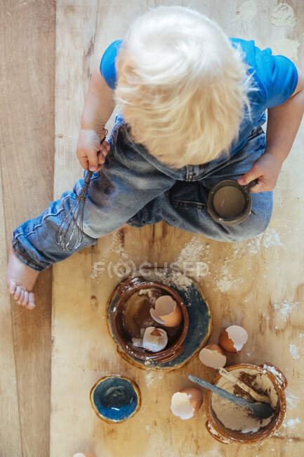 Criança ajudando com a cozinha. Ingredientes ovos, cascas de ovo e flor. — Fotografia de Stock