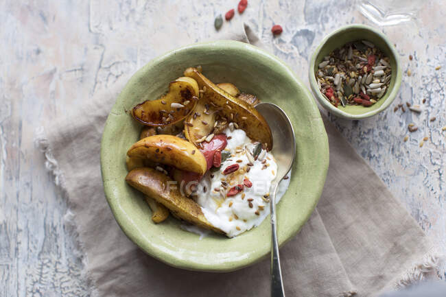 Tranches de pommes et de poires cuites au four, accompagnées de yaourts, de goji et de graines — Photo de stock