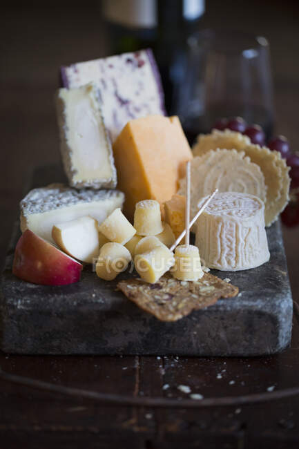 Tabla de quesos bodegón con galletas y frutas - foto de stock