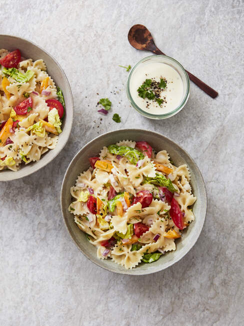 Farfalle-Salat mit Tomaten, Paprika, Petersilie, Zwiebeln und Joghurt-Dressing — Stockfoto