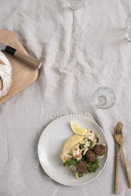 Couve-flor torrada, húmus e falafel com salsa na placa à mesa com pano de linho — Fotografia de Stock