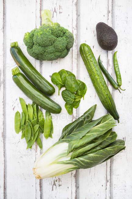 An arrangement of green fruit and vegetables: broccoli, avocado, mange tout, chard, courgette, baby spinach and green chilli peppers — Stock Photo