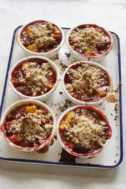 Mango and strawberries with crumbles in ramekins — Stock Photo