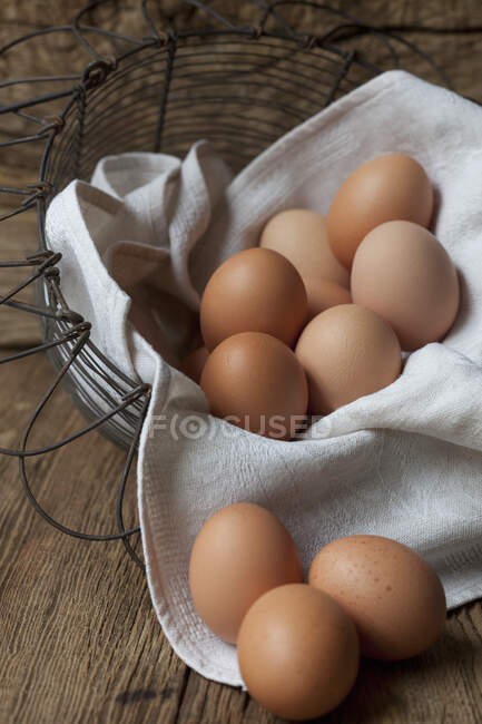 Ovos frescos em um tecido em uma cesta de arame — Fotografia de Stock