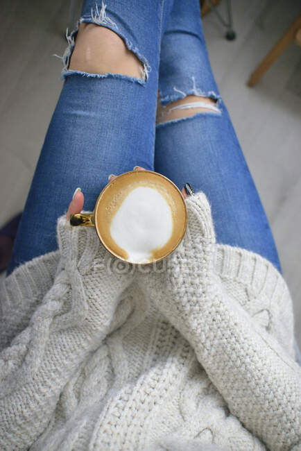 Una mujer sosteniendo una taza de café en sus manos - foto de stock