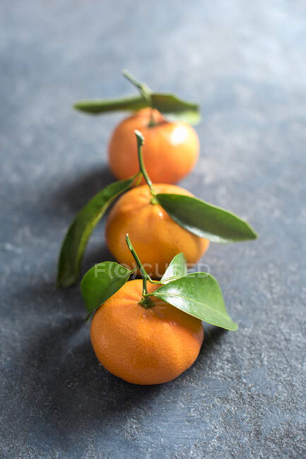Mandarines avec feuilles vertes sur la surface de la pierre — Photo de stock