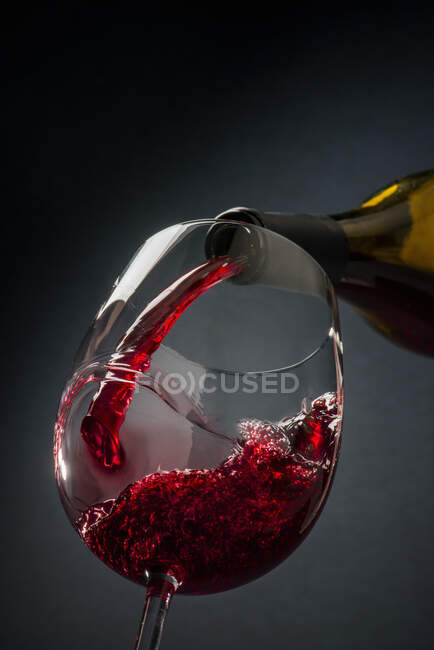 Red wine poured from a bottle into a glass — Fotografia de Stock