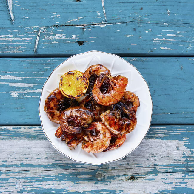 Delicious Grilled Prawns Shrimps on plate with lemon on turquoise vintage table from above — Stock Photo