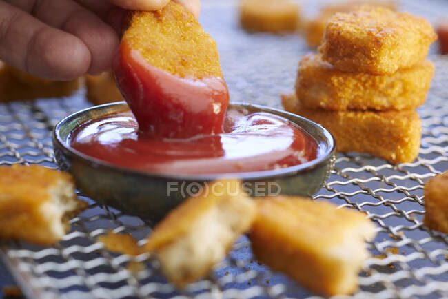 Nuggets de pollo con salsa de tomate; Uno cortado a la mitad - foto de stock
