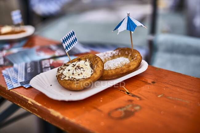 Bavarian doughnuts with powdered sugar, cream and chocolate sprinkles on a wooden table — Stock Photo