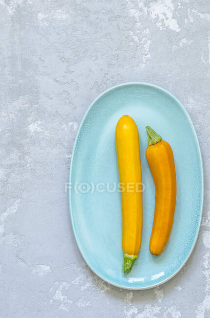 Deux courgettes jaunes sur une assiette bleu pâle — Photo de stock