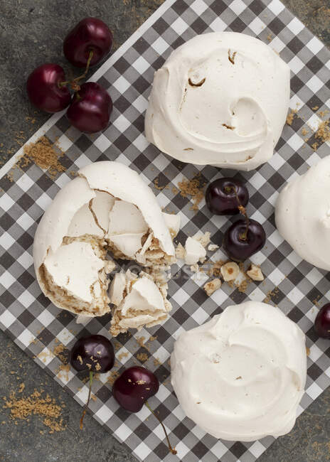 Meringues with fresh Cherries on checkered cloth — Stock Photo