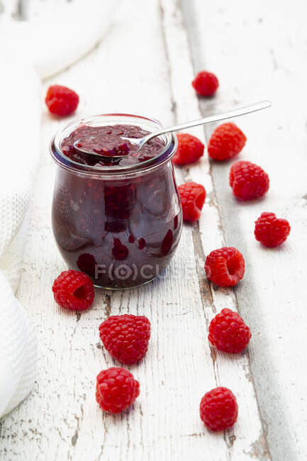 Homemade raspberries jam in jar with spoon and fresh berries on table — Stock Photo