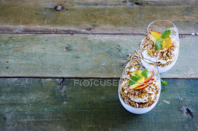Detox Greek yoghurt, granola, peach layered parfait in glasses with mint leaves — Stock Photo