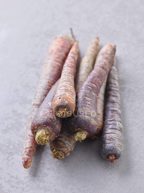 Varias zanahorias moradas en la superficie de piedra - foto de stock