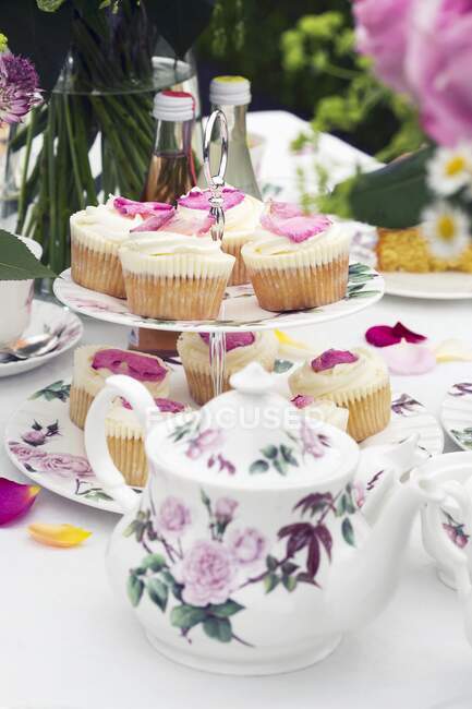 Cupcakes de pétalos de rosa en una mesa puesta para el té - foto de stock
