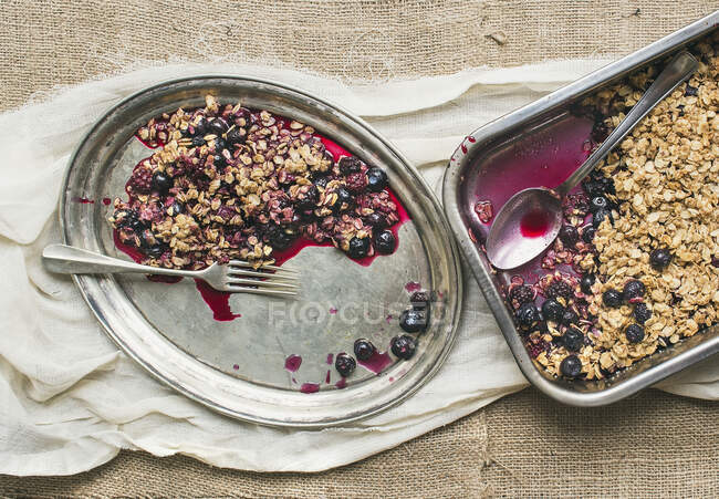 Oat granola with fresh berries on a silver dish with a fork on a sackcloth background — Stock Photo