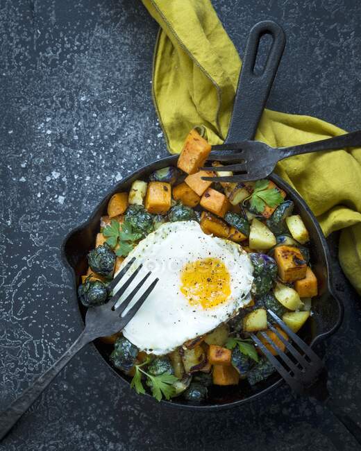 Pan fried sweet potatoes with brussels sprouts, fried egg and parsley — Stock Photo