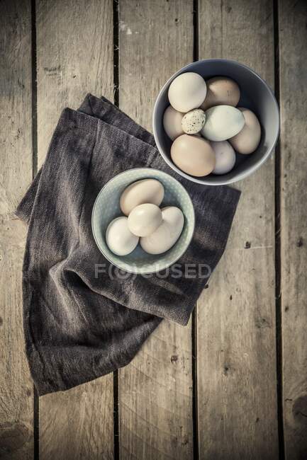 Various eggs in ceramic bowls with cloth — Stock Photo