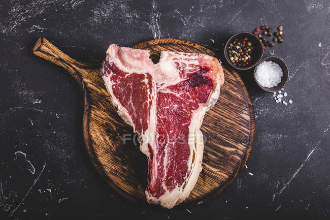 A raw T-bone steak on a wooden board — Stock Photo