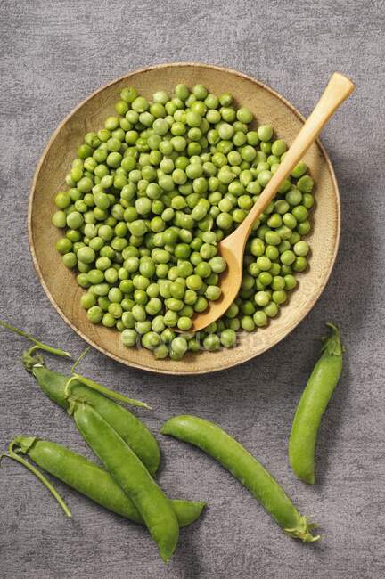 Peas in a wooden bowl with a spoon — Stock Photo