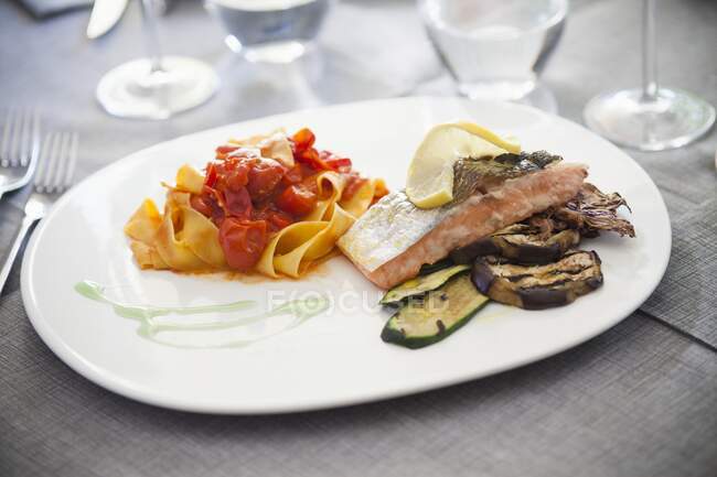 Tagliatelle con tomates y filete de salmón con verduras a la parrilla - foto de stock