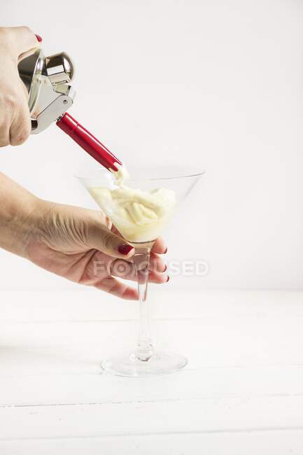 A whipped cream dispenser and cream in a glass — Stock Photo