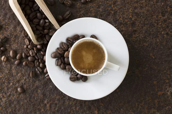 Una taza de café con granos de café en un plato de metal oxidado - foto de stock