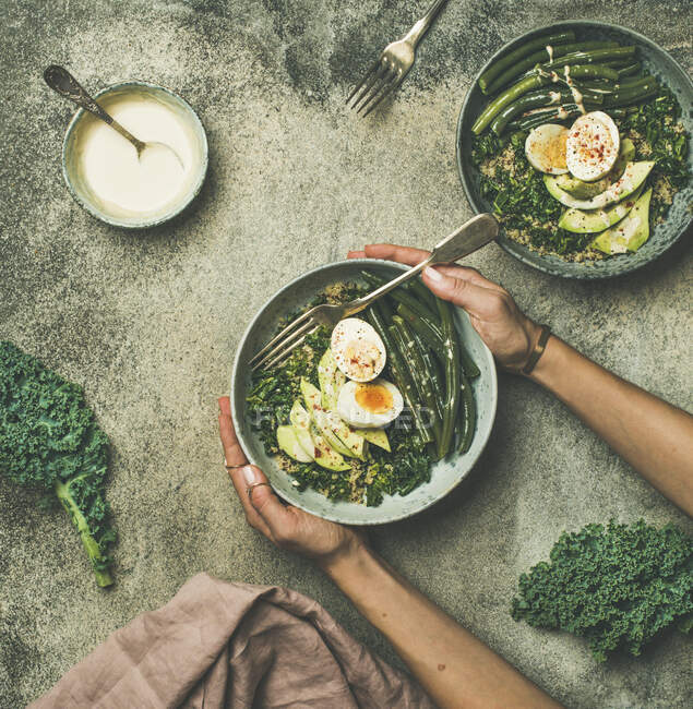 Quinoa, Grünkohl, Bohnen, Avocado, Ei mit cremigem Tahini-Dressing vor grauem Betonhintergrund — Stockfoto