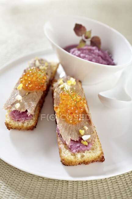 Tartine with tuna fish fillets, caviar and mashed purple potatoes — Stock Photo
