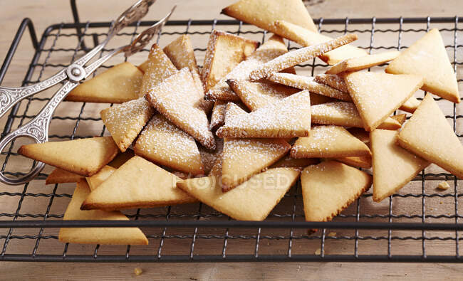 Triangle biscuits with powdered sugar on wire rack - foto de stock