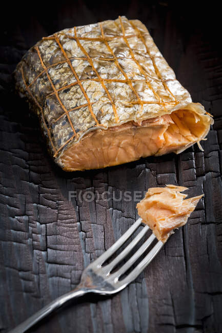 Копченый лосось в сетке с вилкой — стоковое фото