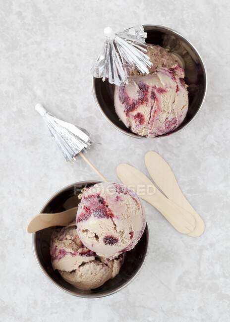 Helado ondulado de chocolate y mora con paraguas de cóctel en tazas de helado (vista superior)) - foto de stock