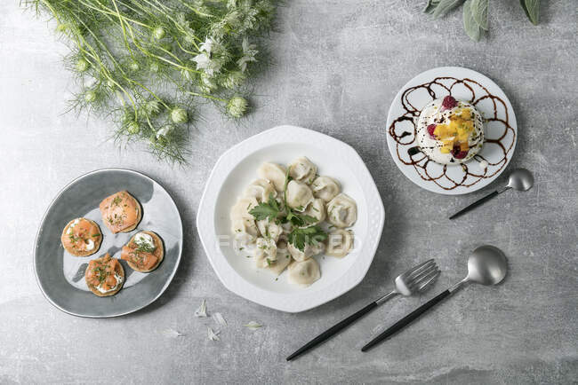 Blinis with salmon, steamed oriental dumplings, and a meringue tartlet - foto de stock
