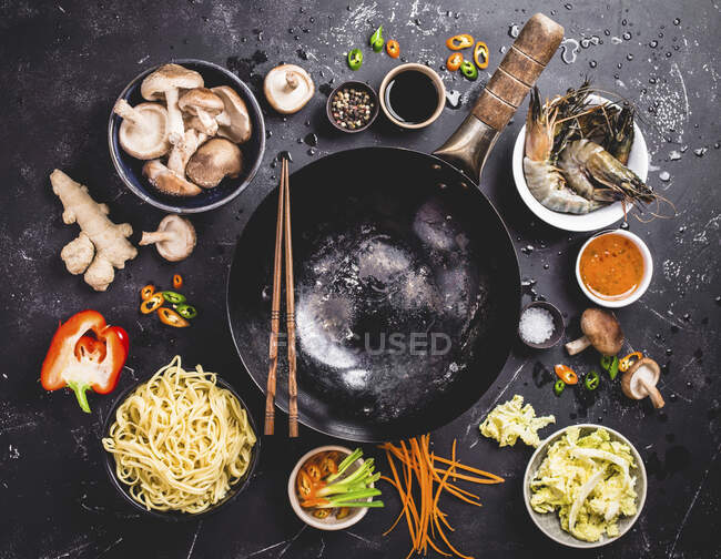 An arrangement of a wok and ingredients for an oriental noodle dish (seen from above) — Stock Photo