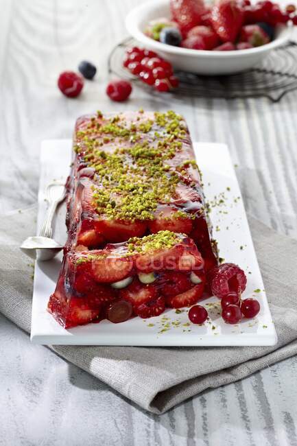 Red berries terrine dessert with grated pistachios — Stock Photo