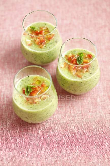 Cold courgette and mint soup garnished with diced red pepper and olive oil — Stock Photo