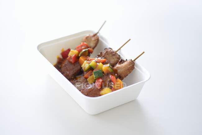 Meat skewers with vegetable sauce in a takeaway box — Stock Photo