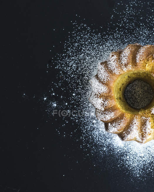 Gâteau au yaourt bundt orange humide avec poudre de sucre, fond sombre grunge — Photo de stock