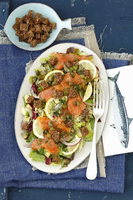 Smoked salmon, lettuce, avocado, capers and croutons salad - foto de stock