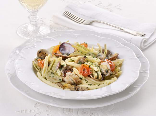 Паста Cavatelli с моллюсками и артишоками на элегантных тарелках — стоковое фото
