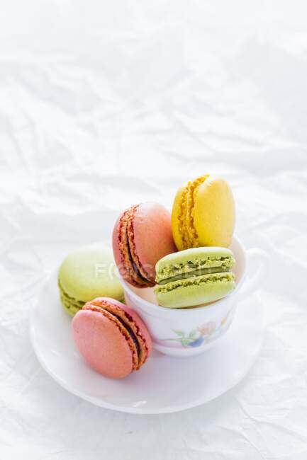 Assortiment de macarons colorés dans une tasse à thé et sur une soucoupe — Photo de stock