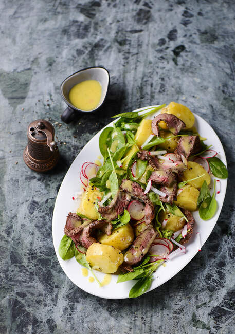 Potato salad with baby spinach and steak stripes — Stock Photo
