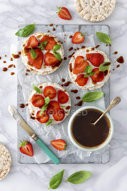 Rice crackers with cream cheese, strawberries, basil and syrup — Stock Photo