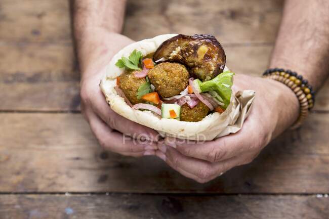 Hands holding a pita bread with falafel — Stock Photo