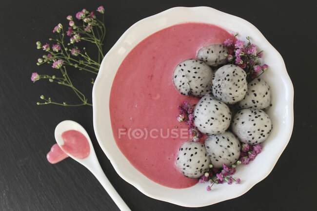 Un tazón de batido rosa con bolas de fruta de dragón - foto de stock