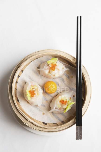 Steamed Chinese dumplings with prawns and fish roe in bamboo steaming basket with chopsticks — Stock Photo